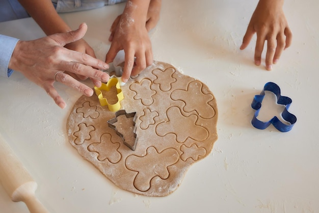 Cerrar la imagen de la mano de un niño pequeño presionando un cortador de galletas con forma de corazón en una masa blanda para hacer galletas de azúcar