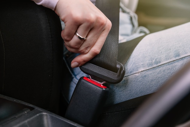 Cerrar imagen de mujer de negocios sentada en un coche poniéndose el cinturón de seguridad