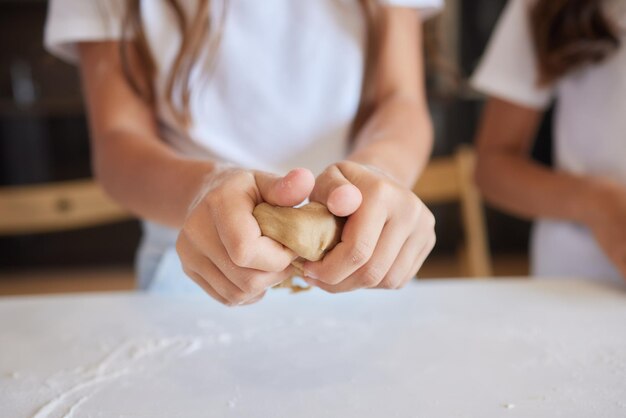 Cerrar imagen mujer y pequeña hija amasar con las manos mesa de madera en polvo con harina