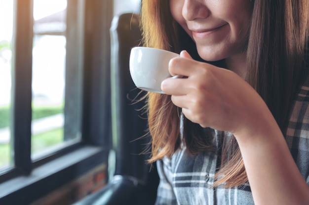 Cerrar imagen de mujer sosteniendo y bebiendo café caliente con sentirse bien en la cafetería