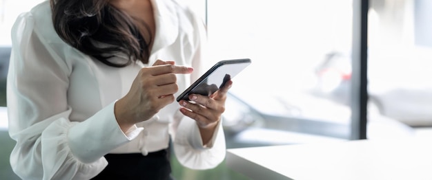 Foto cerrar joven empresaria a través de teléfono móvil en la oficina moderna