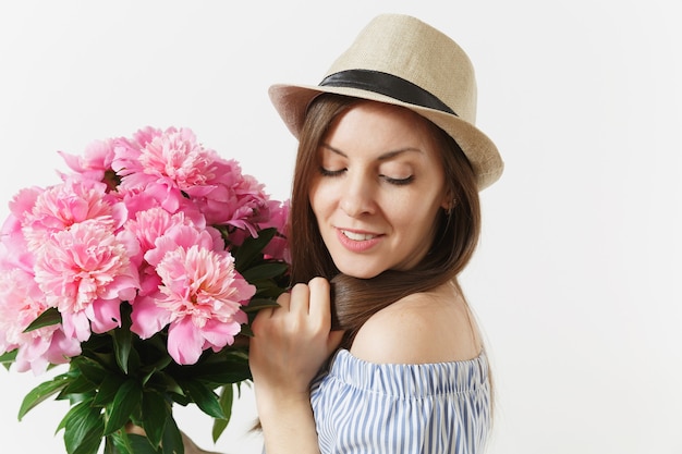 Cerrar joven tierna en vestido azul, sombrero con ramo de flores de peonías rosas aisladas sobre fondo blanco. Día de San Valentín, concepto de vacaciones del Día Internacional de la Mujer. Área de publicidad.