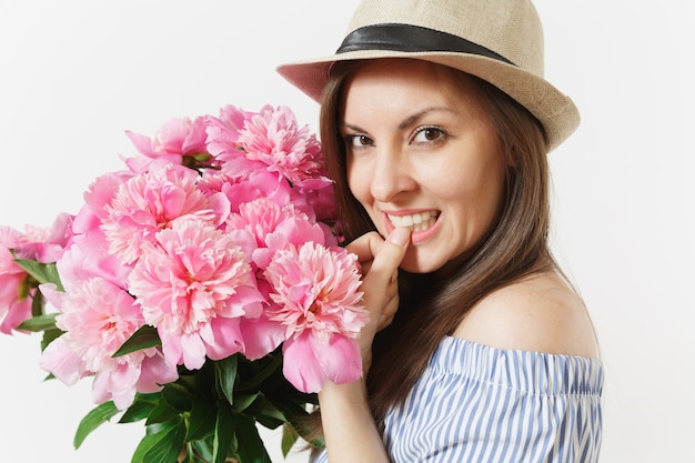 Cerrar joven tierna en vestido azul, sombrero con ramo de flores de peonías rosas aisladas sobre fondo blanco. Día de San Valentín, concepto de vacaciones del Día Internacional de la Mujer. Área de publicidad.