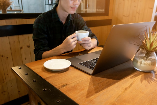 Cerrar joven trabajando con su computadora en la cafetería