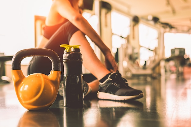 Cerrar kettlebells con entrenamiento de ejercicio de mujer en gimnasio gimnasio rompiendo relajarse después de deporte