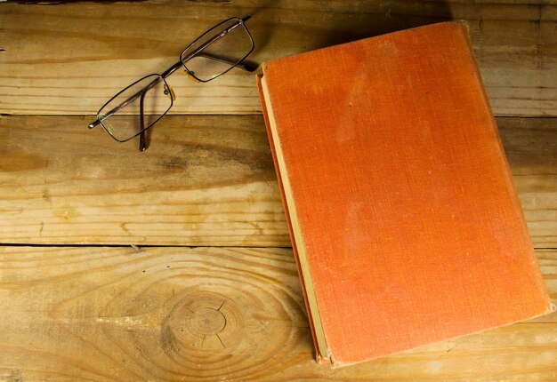 Cerrar libro antiguo con gafas en el fondo de madera