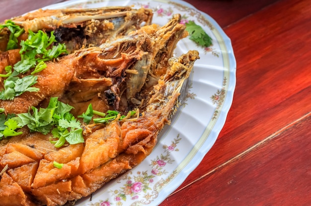 Cerrar la lubina frita con salsa de pescado (Pla Ga Pong Tod Nam Pla) en el plato decorar con hojas de perejil de cilantro