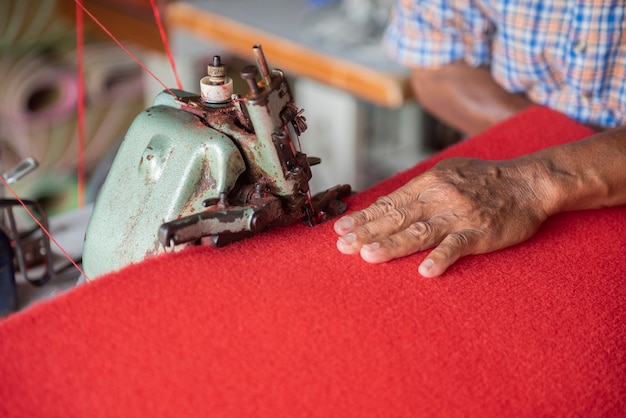 Cerrar la mano del anciano cosiendo una alfombra roja