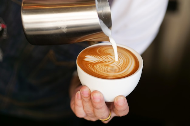 cerrar la mano del barista haciendo una taza de café.