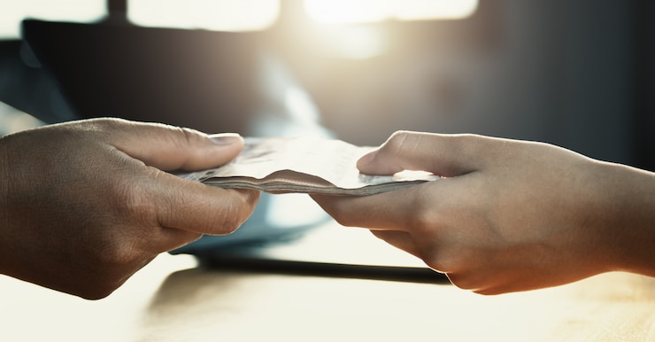 Foto cerrar mano dando dinero para socio en escritorio