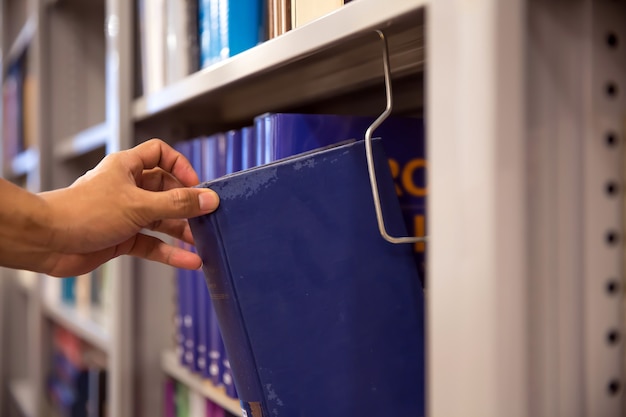 Cerrar la mano eligiendo un libro de la estantería.