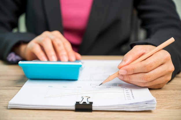 Foto cerrar la mano de la empresaria utilizando la máquina de cálculo de las finanzas del hogar o impuestos sobre la máquina, conceptos financieros y contables,