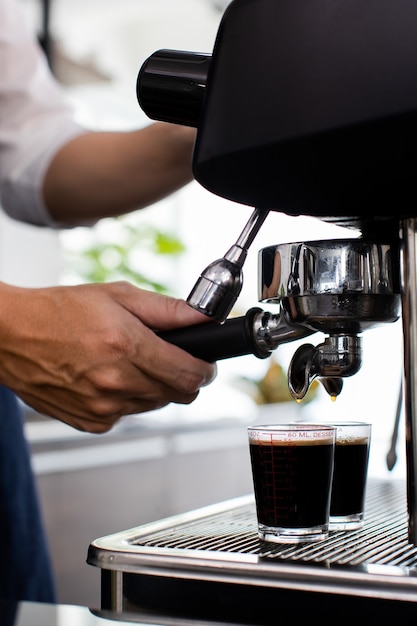 Cerrar la mano. Hacer una taza de café en una máquina de café, el vapor y la taza. Máquina cafetera espresso con portafiltro de cerca. Concepto Cafetera en café.