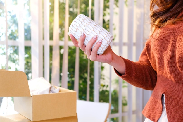 Cerrar la mano de una hermosa mujer asiática sosteniendo un producto de jarrón para vender en línea en vivo en casa Chica atractiva joven que muestra los detalles de los productos a los clientes Concepto de compras en línea