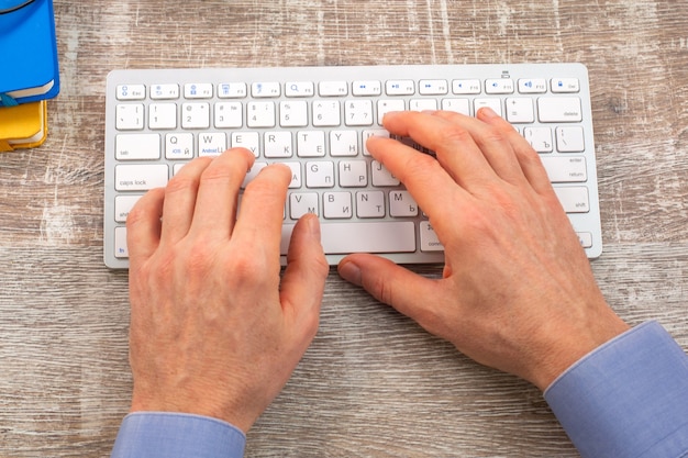 Cerrar la mano del hombre escribiendo en el teclado blanco