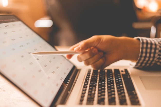 Cerrar la mano del hombre de negocios con una sartén mirando los detalles del mercado de valores en las computadoras portátiles