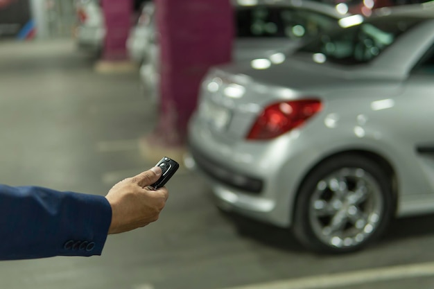 Cerrar la mano de un hombre Presione el botón del control remoto de las llaves del automóvil para bloquear y desbloquear la puerta del automóvil