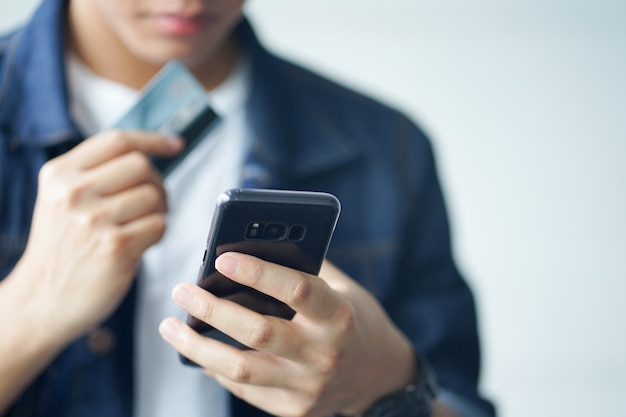 cerrar la mano del hombre sosteniendo el teléfono inteligente y tratando de pagar con tarjeta de crédito