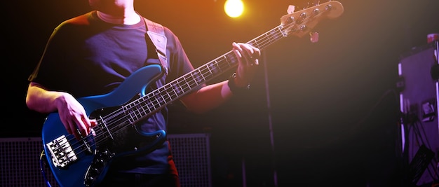 Cerrar mano joven tocando el bajo en el estudio de grabación base de ensayo de la banda de música rock