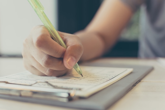 Cerrar mano mujer asiática escribiendo en papel