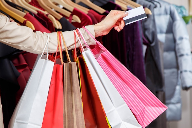 Cerrar la mano de la mujer con muchos bolsos de compras y tarjeta de crédito