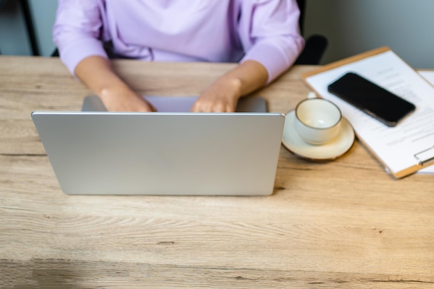 Cerrar la mano de una mujer de negocios escribiendo una computadora portátil con teclado en la oficina de escritorio