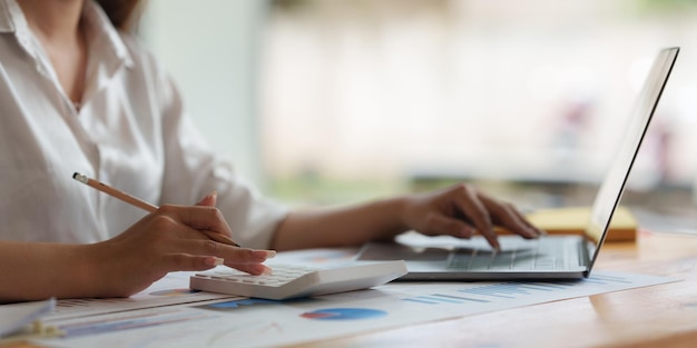 Cerrar la mano de una mujer de negocios usando una calculadora para calcular los resultados financieros y el presupuesto de la empresa Concepto de auditoría de cuentas