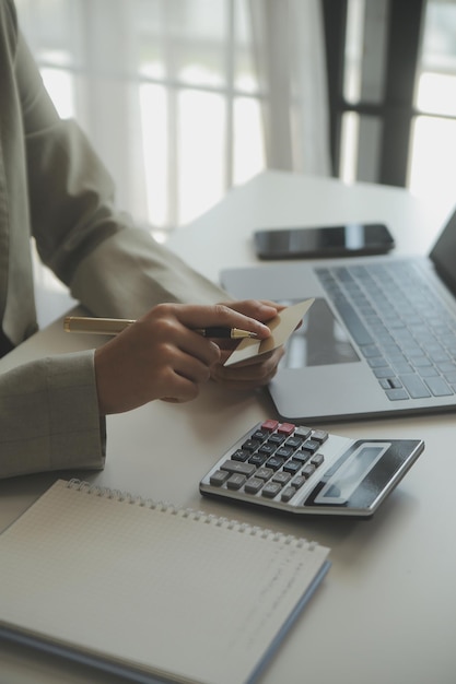 Cerrar la mano de la mujer con tarjeta de crédito y computadora portátil con teléfono inteligente para comprar compras en línea