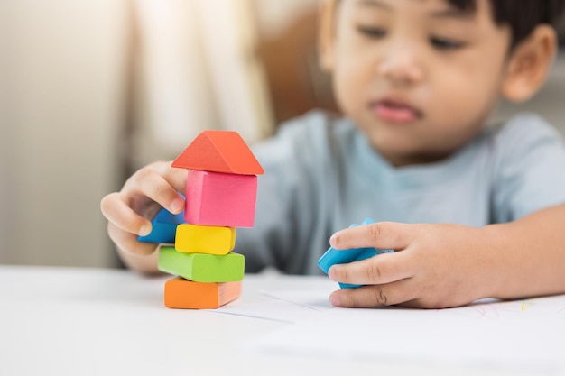 Cerrar Mano de los niños Practicar las habilidades de jugar con juguetes de madera sobre la mesa en la sala de estar Educación de niños pequeños asiáticos desde casa Desarrollar el aprendizaje de los niños antes de ingresar al jardín de infantes