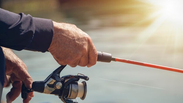 Cerrar en la mano del pescador sosteniendo una caña de pescar