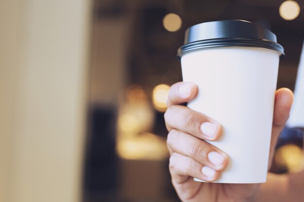 Cerrar la mano que sostiene la taza de café de papel para llevar.