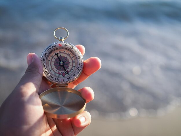 Cerrar la mano sosteniendo la brújula con el fondo de la playa