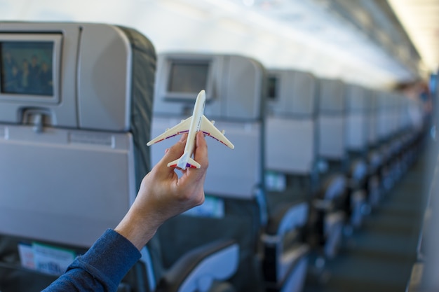 Cerrar una mano sosteniendo un modelo de avión dentro de un avión grande