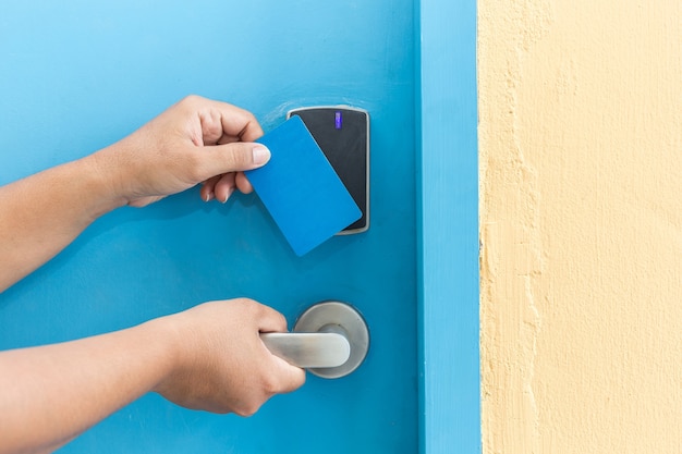 Cerrar una mano sosteniendo la tarjeta azul del hotel frente a la puerta eléctrica