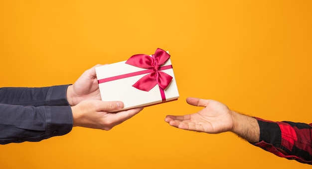 Foto cerrar las manos dando la presente caja de regalo en el día de navidad en amarillo