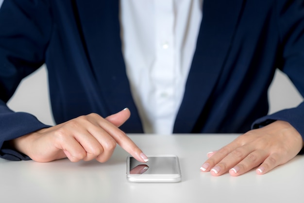 Cerrar las manos de la empresaria con smartphone en pantalla en blanco