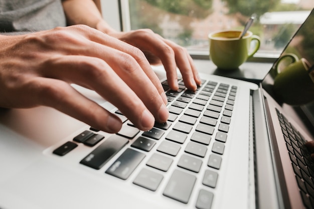 Foto cerrar las manos escribiendo en la computadora portátil