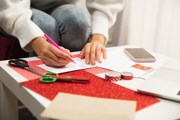 Cerrar las manos femeninas haciendo tarjetas de felicitación para Navidad y Año Nuevo