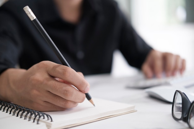 Cerrar las manos con lápiz escribiendo en el cuaderno. Concepto de educación.