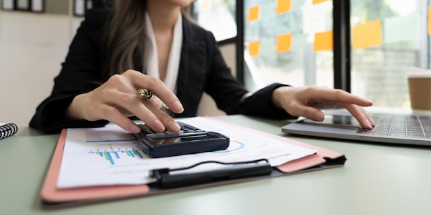 Cerrar manos mujer contable de negocios haciendo finanzas con el uso de la calculadora y el uso de la computadora portátil