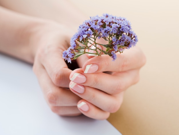 Foto cerrar las manos de mujer sosteniendo flores púrpuras