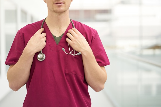 Cerrar médico hombre caucásico con estetoscopio en el cuello, weared en traje médico de Borgoña