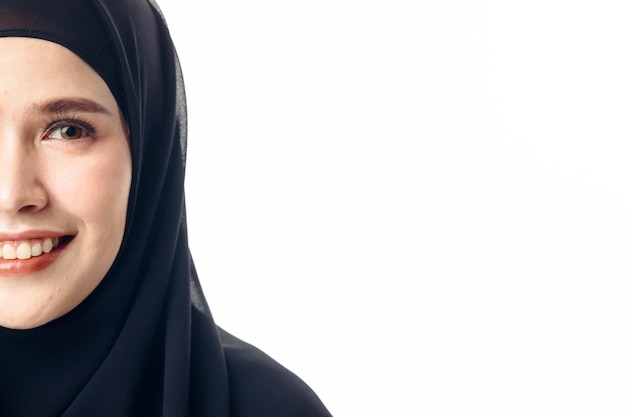 Cerrar la mitad de la cara del modelo de mujer islámica sonriendo y posando sobre fondo blanco aislado