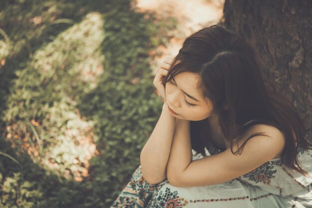 Cerrar mujer asiática triste sentarse bajo el concepto de niña de árbol styleheartbreak vintage