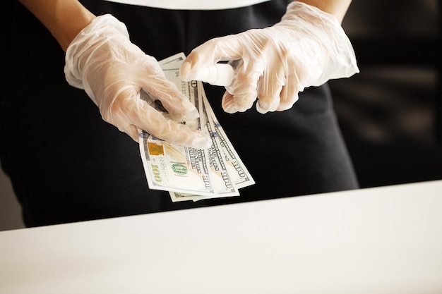 Foto cerrar mujer desinfectar dinero con antiséptico.