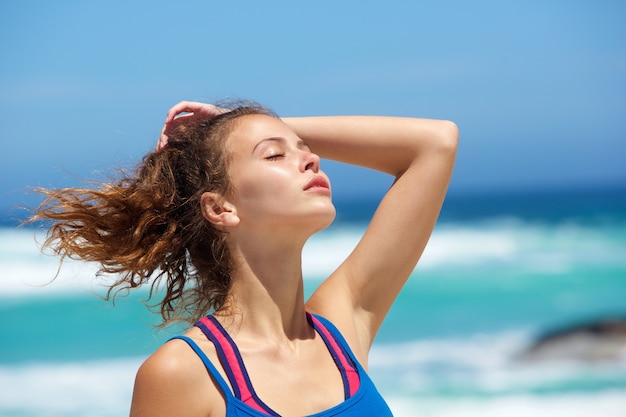 Cerrar una mujer joven en la playa con la mano en el pelo