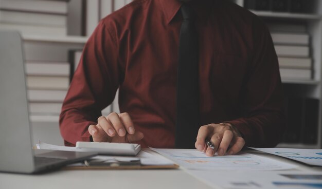 Foto cerrar mujer de negocios usando calculadora y computadora portátil para hacer matemáticas finanzas en escritorio de madera estadísticas de contabilidad fiscal y concepto de investigación analítica