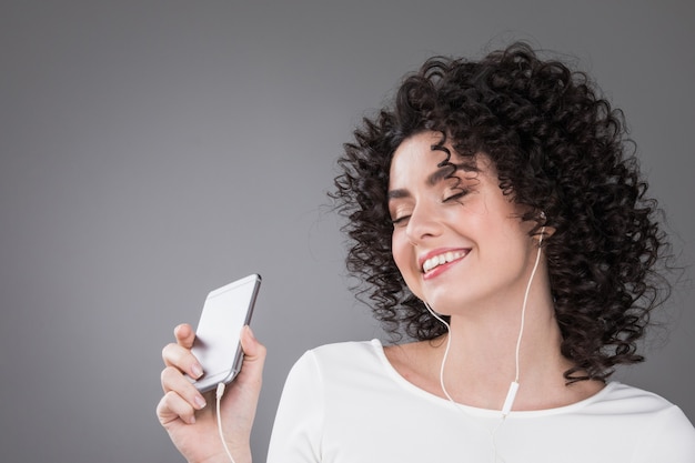 Foto cerrar mujer rizada escuchando música