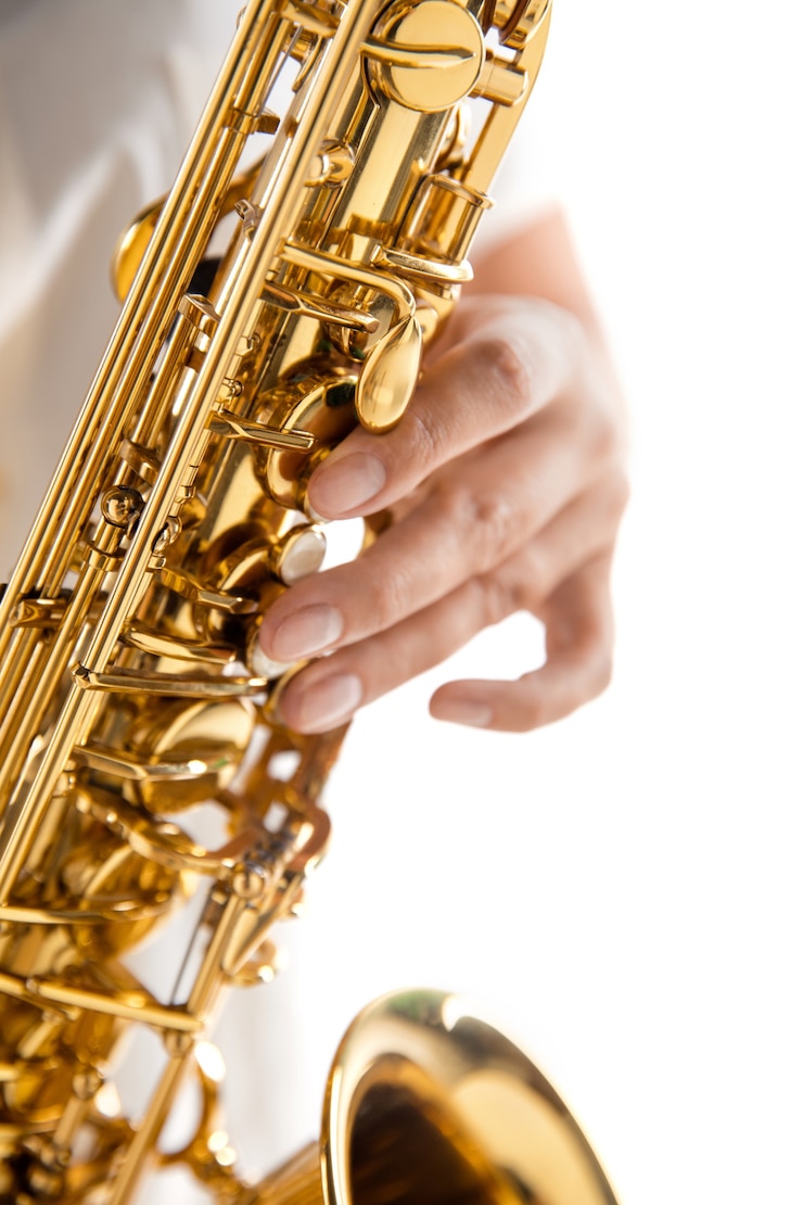 Foto cerrar mujer tocando el saxofón aislado sobre fondo blanco de estudio. músico inspirado, detalles de la ocupación artística, instrumento clásico mundial para jazz y blues. concepto de afición, creatividad.