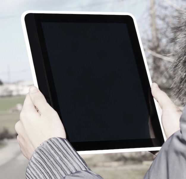 Cerrar mujer usando tableta digital al aire libre